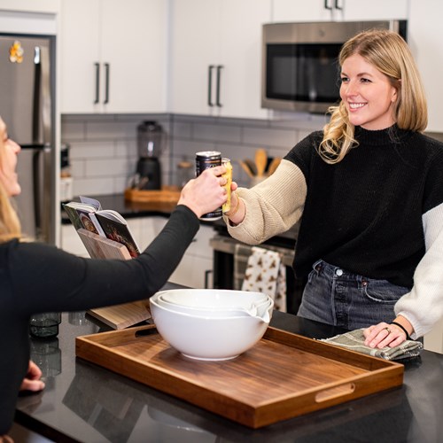 two women cheersing a beverage in the kitchen