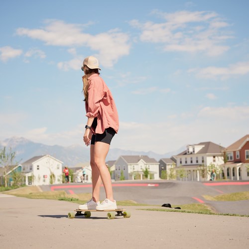 Photograph of someone riding a skateboard through a residential neighborhood near the Novel Daybreak apartments. 