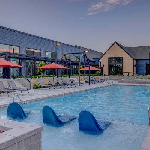 The pool area at our apartments for rent in Salt Lake, Utah, featuring umbrellas, lounge chairs, and a clubhouse.