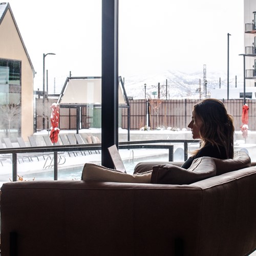 silhouette of woman sitting on the couch with snow and the pool in the background